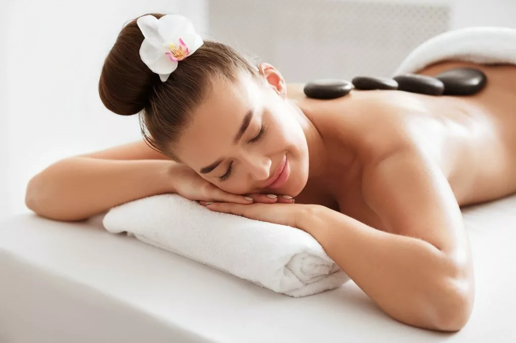 relaxed woman enjoying hot stone massage at spa 1 1024x682 1 jpg